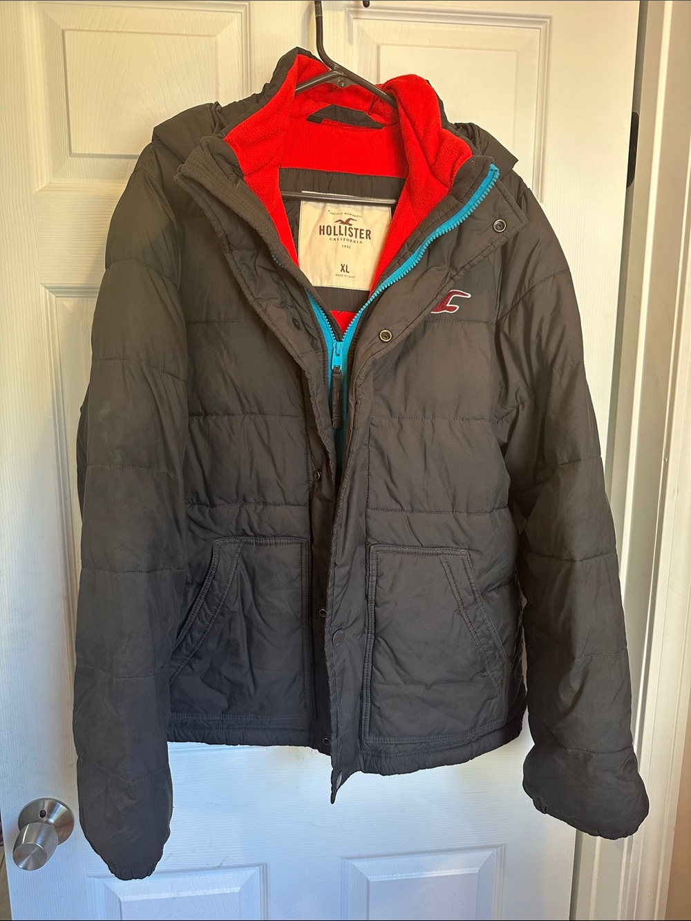 Hollister Men's Black Puffer Jacket with Red Lining and Blue Zip Detail